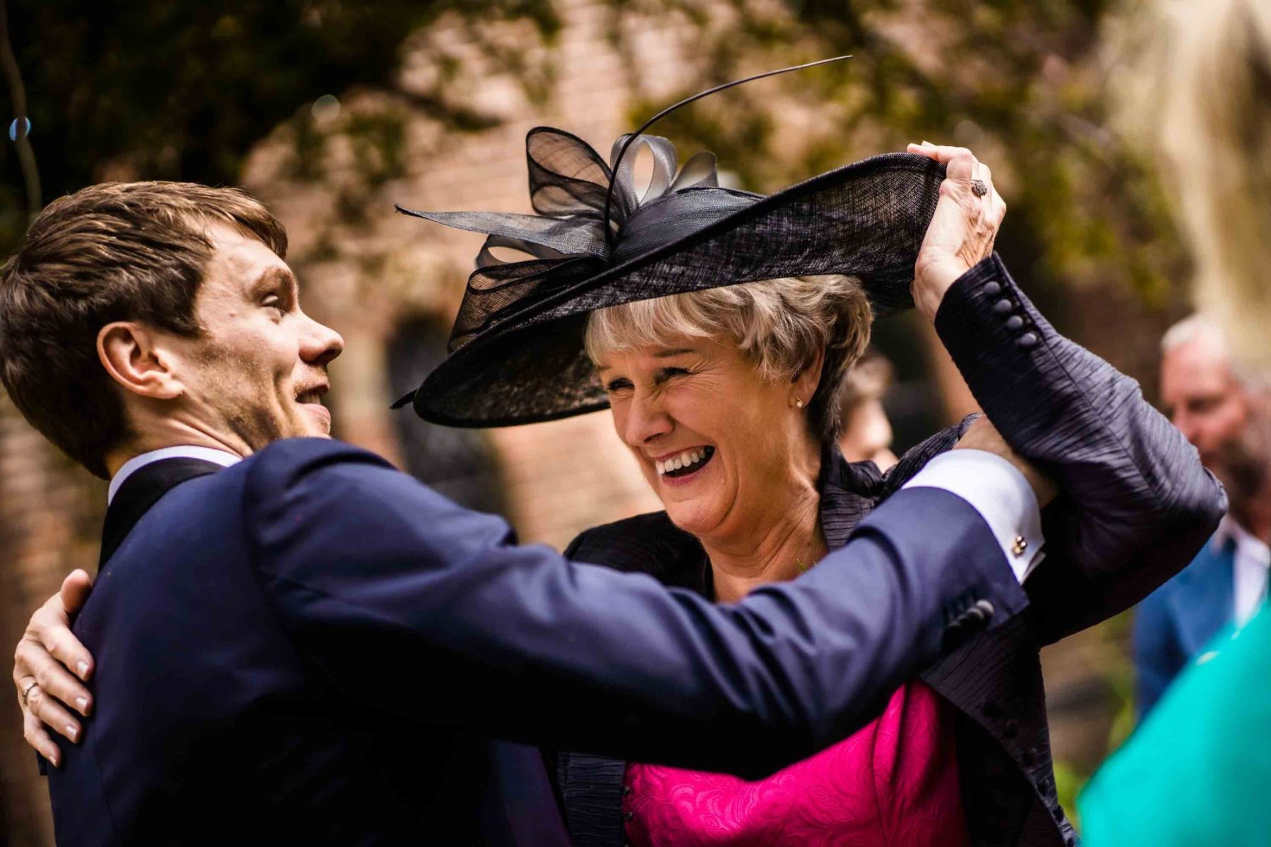 Groom hugging his mother in big hat