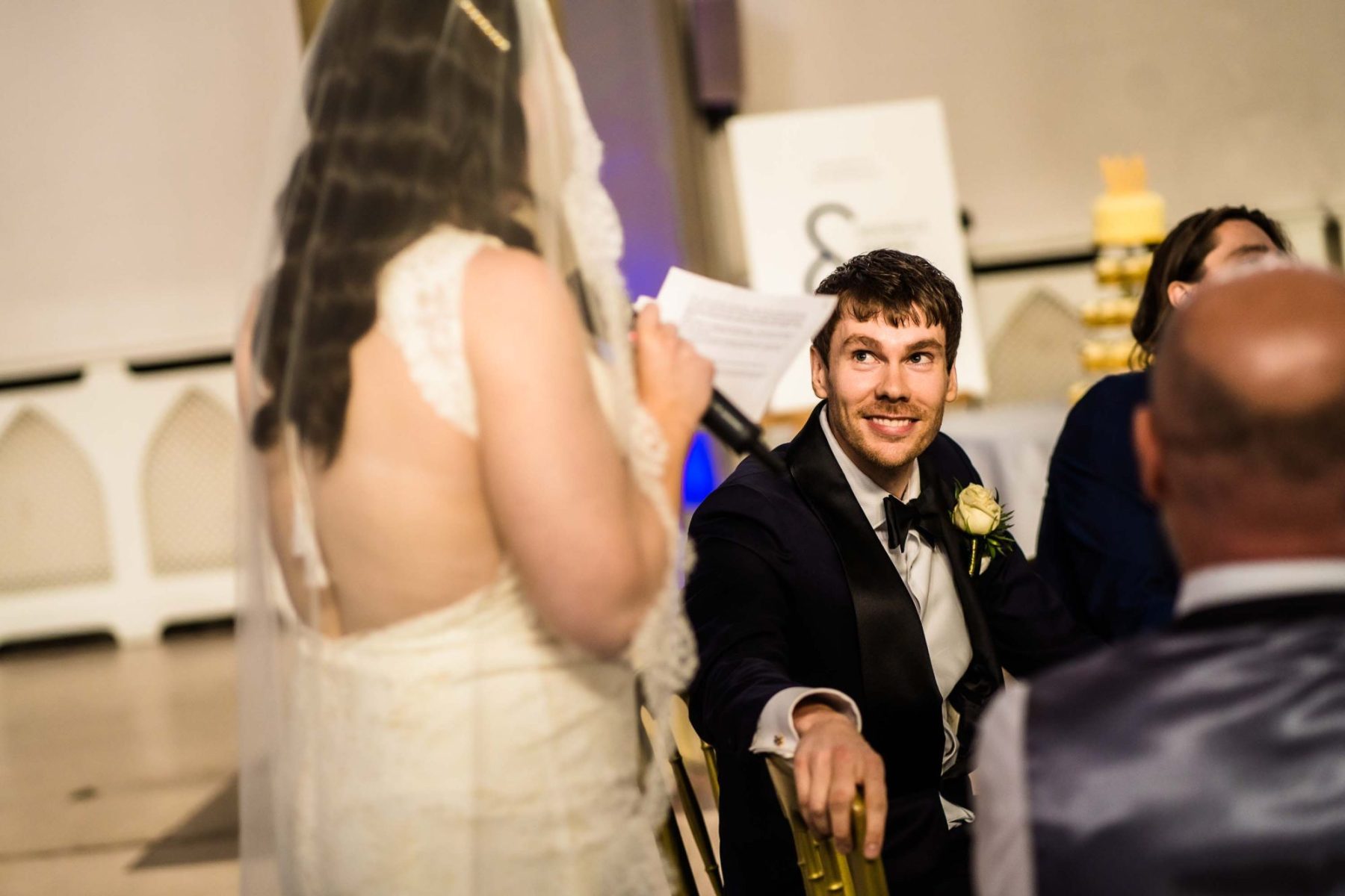 Groom looking at bride as she makes her speech