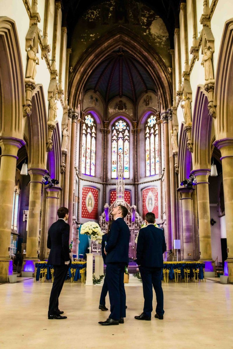 Groomsmen looking up at ceiling at Gorton Monastery