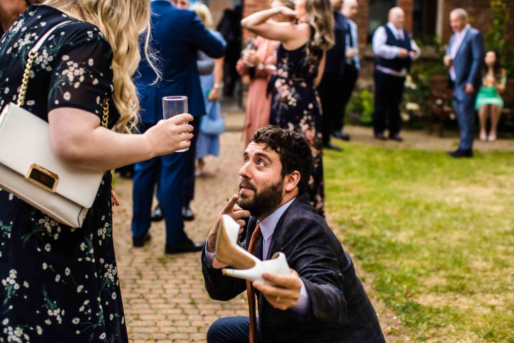 Man kneeling down with womans high heeled shoe in his hand